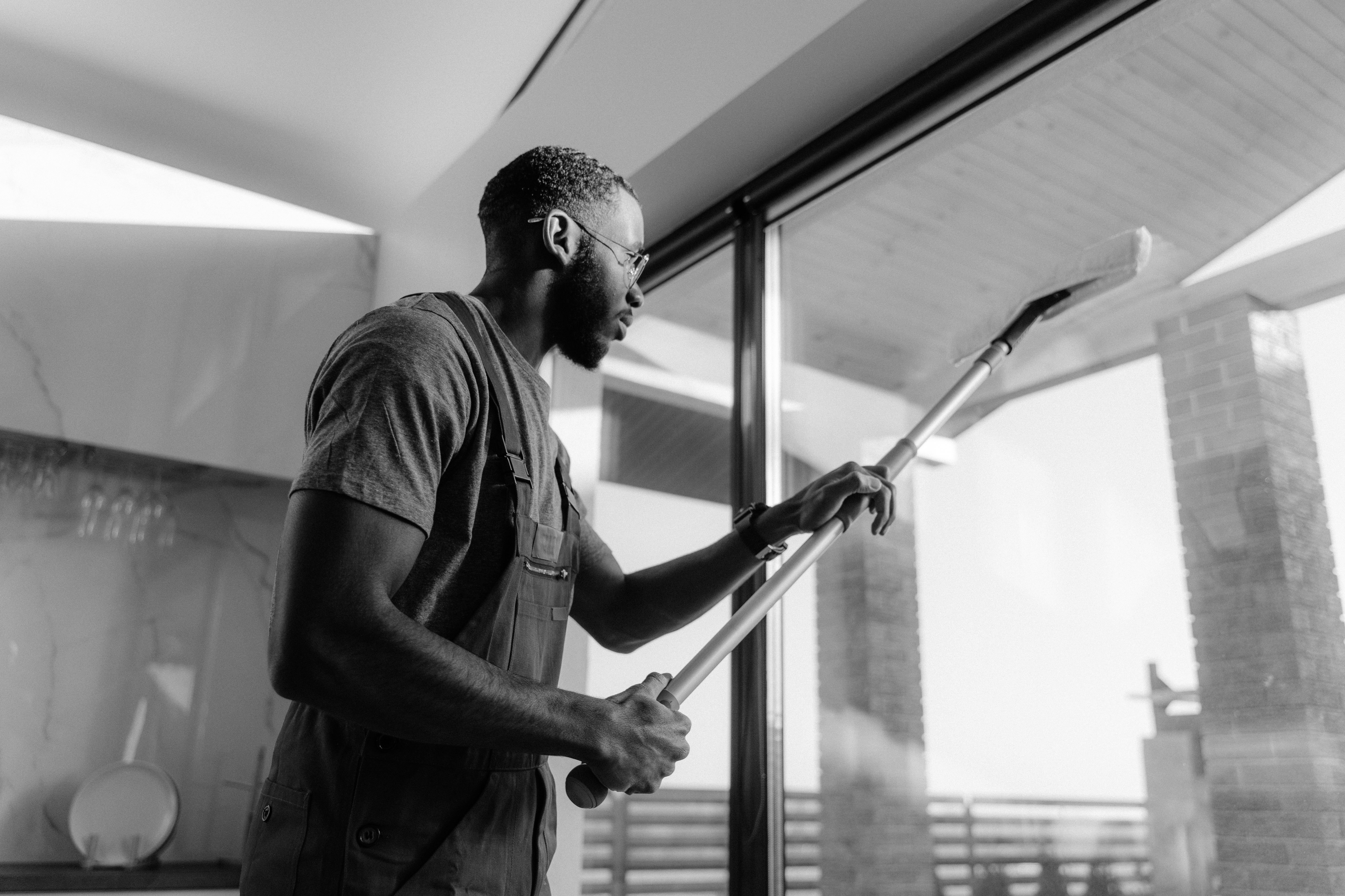 Professionele schoonmaker reinigt een groot glazen paneel in een modern gebouw.