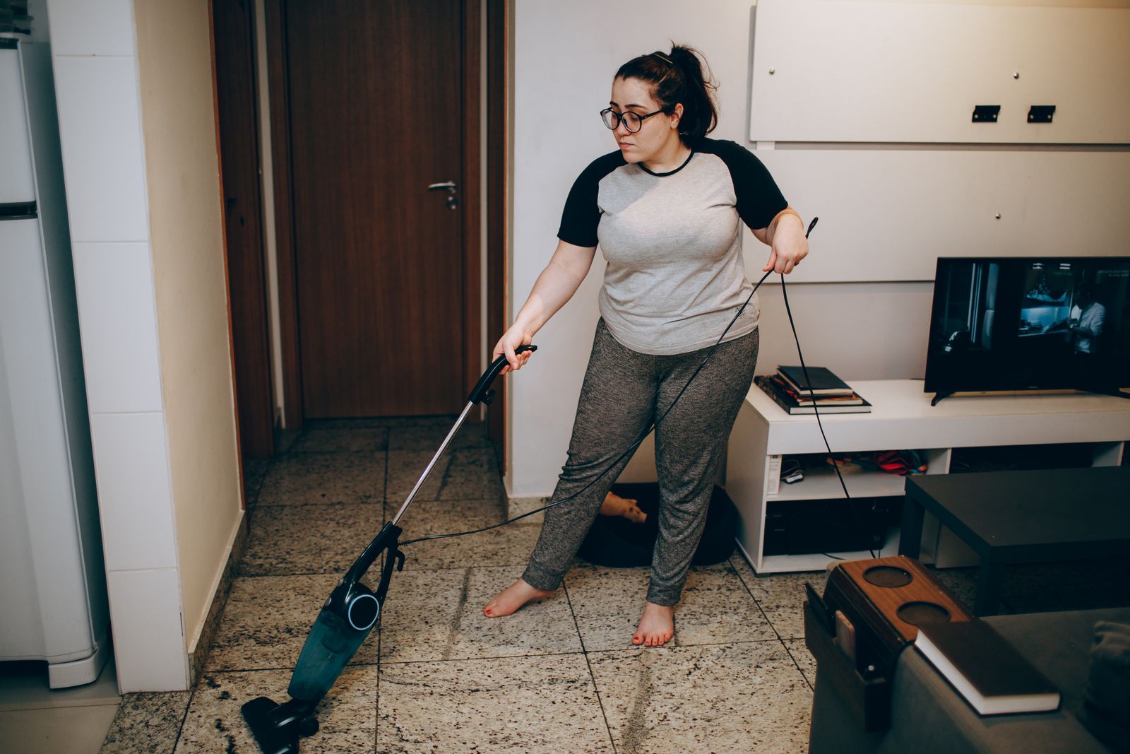 Een vrouw stofzuigt een lichte woonkamer.